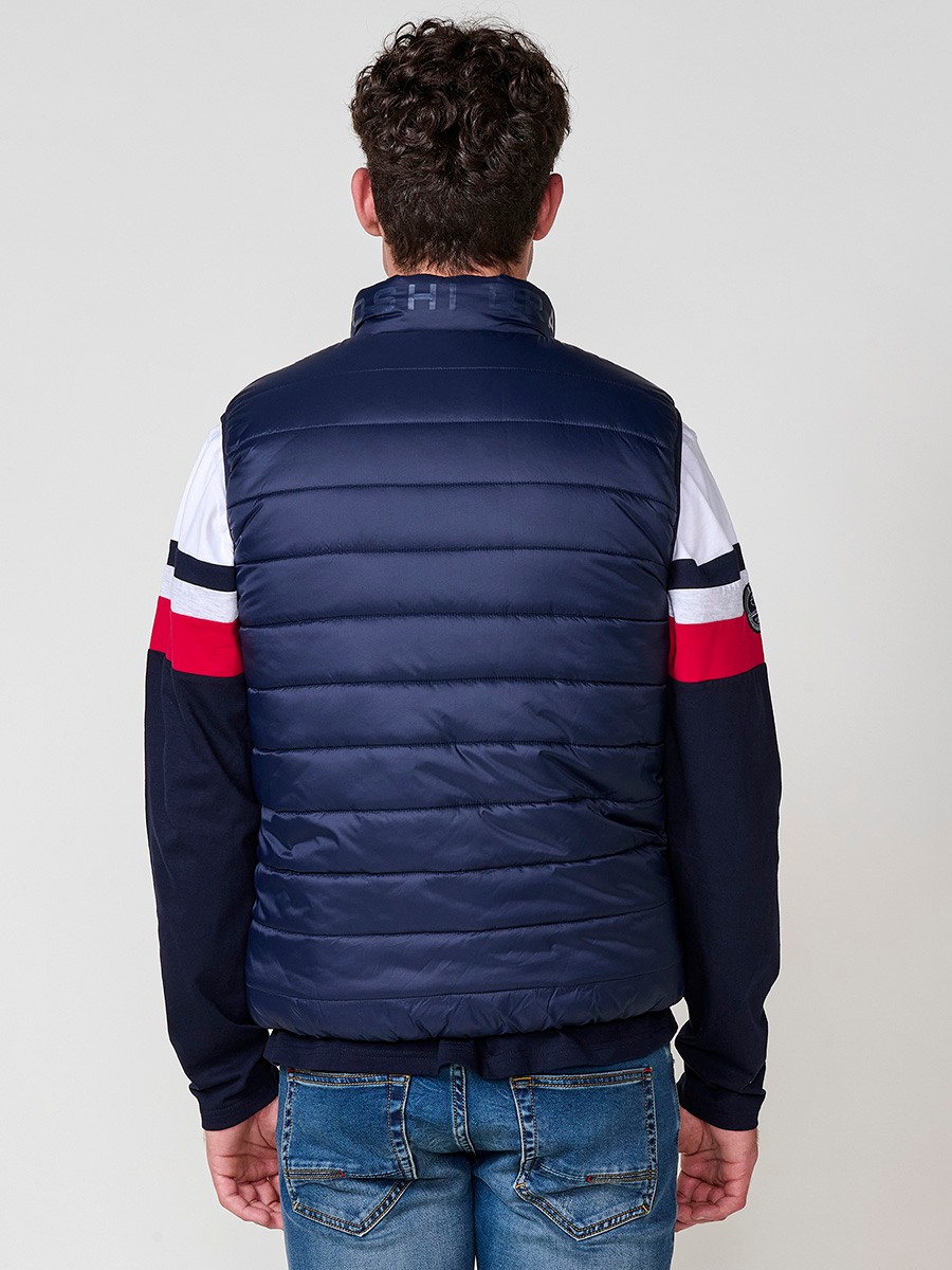 Armilla encoixinada reversible d’home navy amb coll alt i cremallera. Confeccionada en 100 % polièster, pràctica, lleugera i versàtil.
