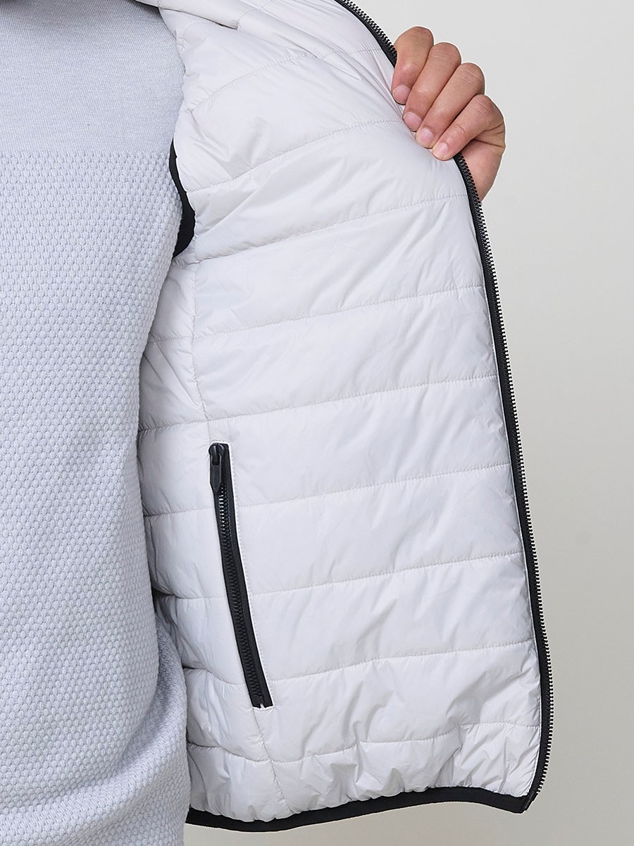 Armilla encoixinada reversible d’home gris perla amb coll alt i cremallera frontal. Confeccionada en 100 % polièster, pràctica, lleugera i versàtil.