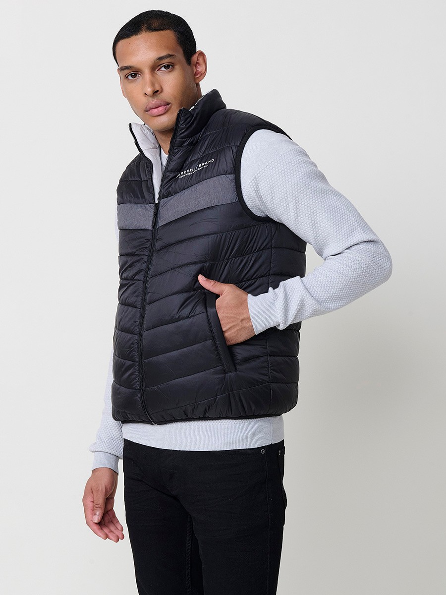 Armilla encoixinada reversible d’home gris perla amb coll alt i cremallera frontal. Confeccionada en 100 % polièster, pràctica, lleugera i versàtil.