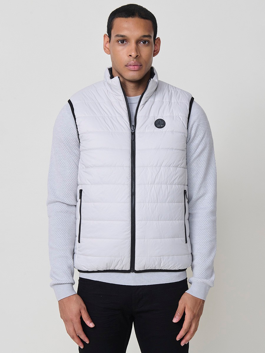 Armilla encoixinada reversible d’home gris perla amb coll alt i cremallera frontal. Confeccionada en 100 % polièster, pràctica, lleugera i versàtil.