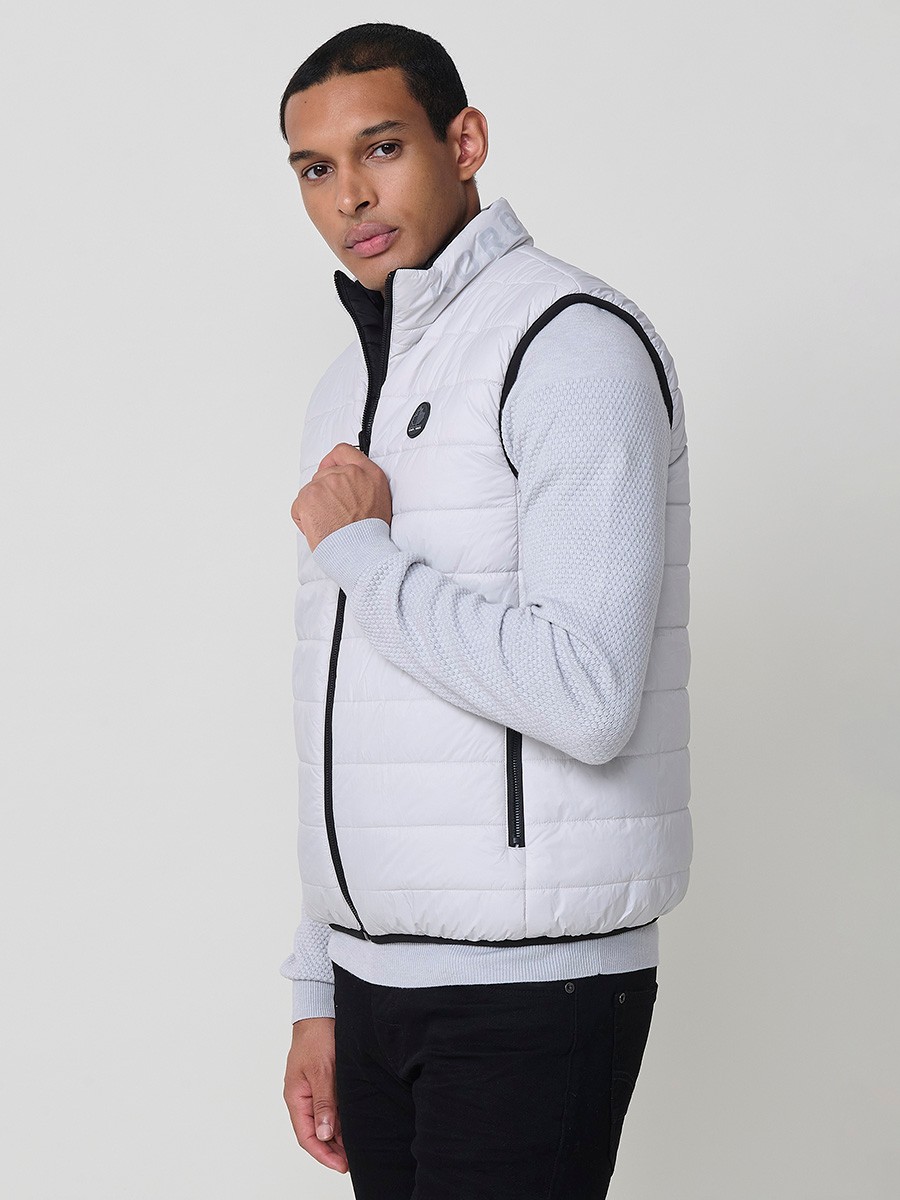 Armilla encoixinada reversible d’home gris perla amb coll alt i cremallera frontal. Confeccionada en 100 % polièster, pràctica, lleugera i versàtil.