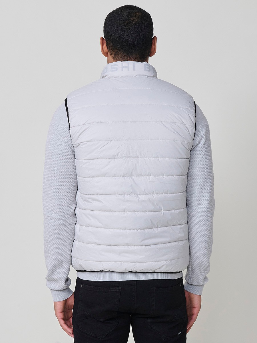 Armilla encoixinada reversible d’home gris perla amb coll alt i cremallera frontal. Confeccionada en 100 % polièster, pràctica, lleugera i versàtil.