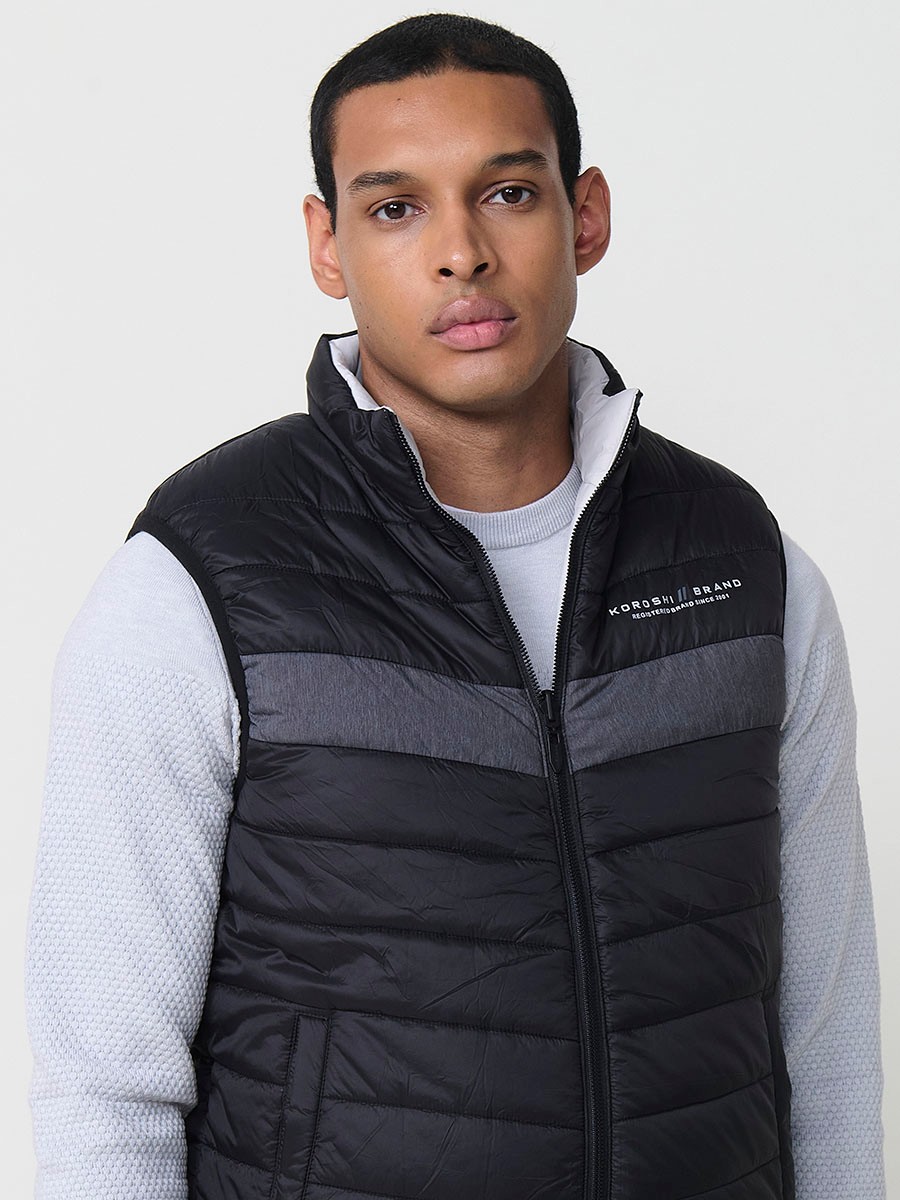 Armilla encoixinada reversible d’home gris perla amb coll alt i cremallera frontal. Confeccionada en 100 % polièster, pràctica, lleugera i versàtil.