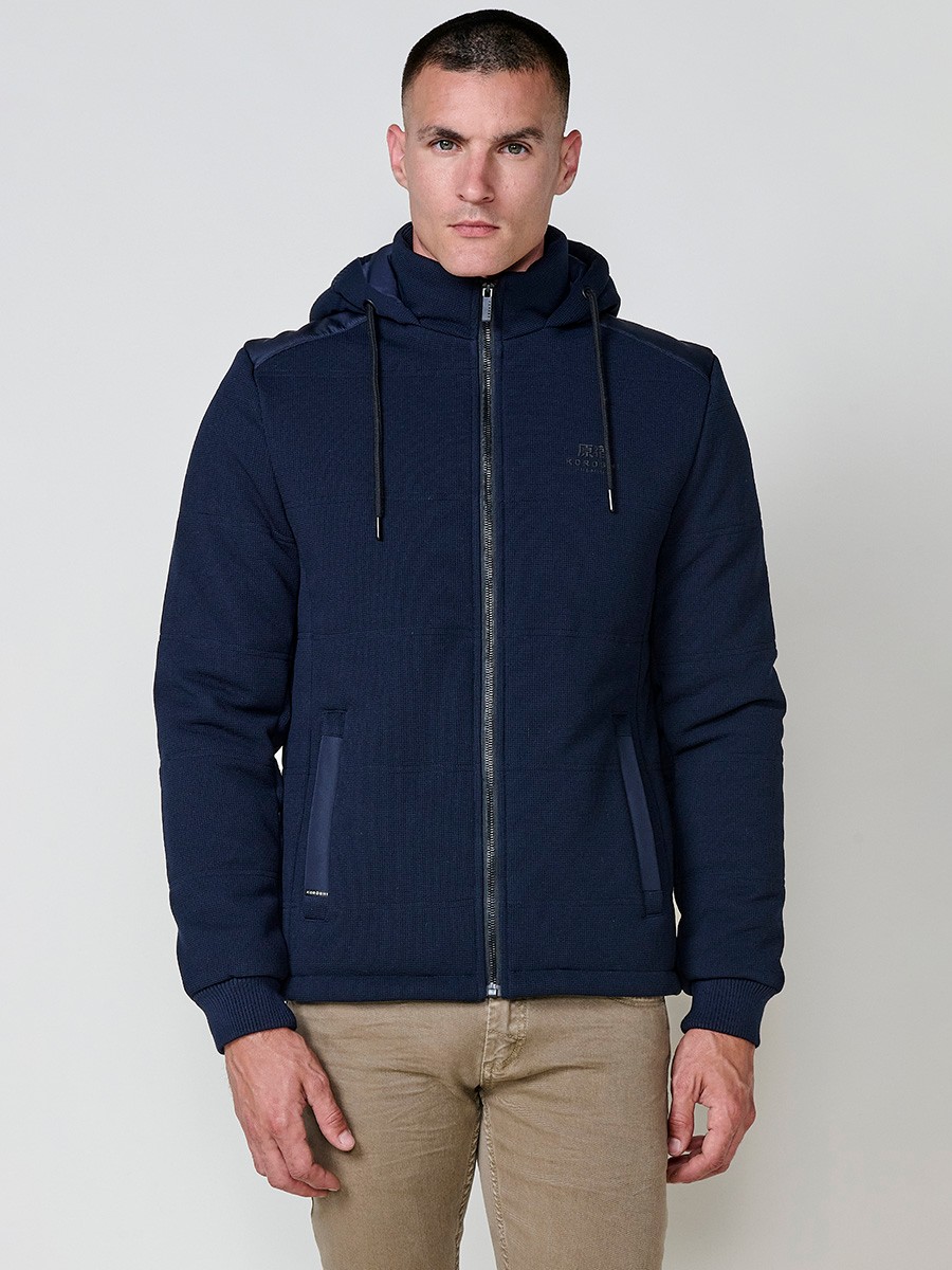 Gesteppte Herrenjacke in Navy mit abnehmbarer Kapuze, hohem Kragen und Reißverschluss. Aus 100 % Polyester, warm, strapazierfähig und vielseitig.