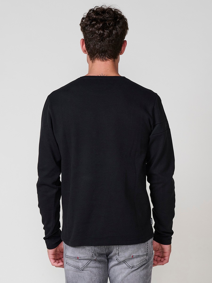 Camiseta de hombre en color negro, manga larga, cuello redondo con abertura y estampado delantero. Confeccionada en 100% algodón.