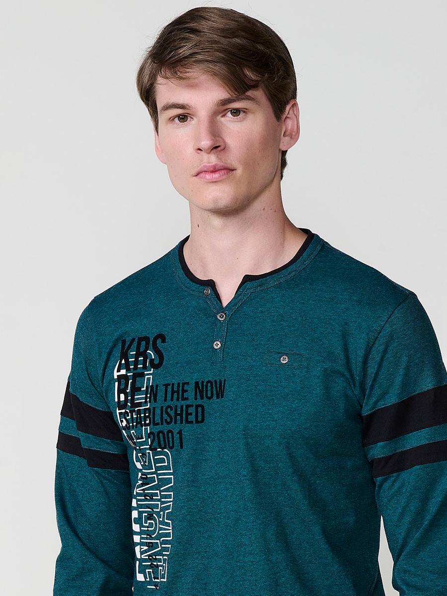 Camiseta de hombre en color petróleo, manga larga, cuello redondo con abertura y estampado delantero. Confeccionada en 100% algodón.