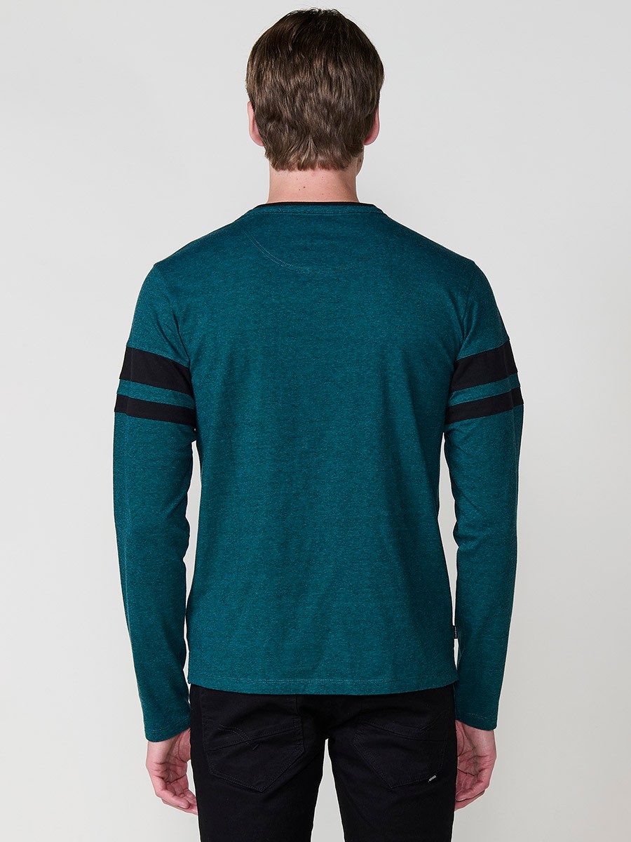 Camiseta de hombre en color petróleo, manga larga, cuello redondo con abertura y estampado delantero. Confeccionada en 100% algodón.