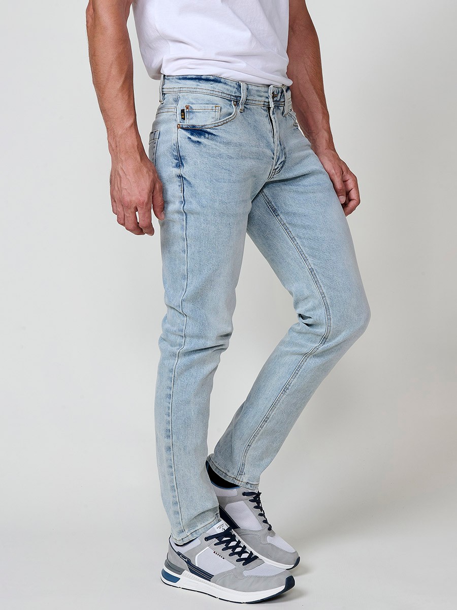 Pantalón jeans stretch para hombre en azul claro, corte regular fit. Cierre delantero con cremallera y botón.