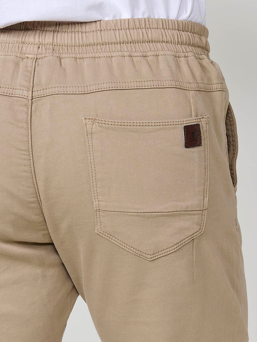Pantalón jogger de hombre en color beige, con bolsillos laterales, cintura elástica y tejido 100% poliéster cómodo y resistente.