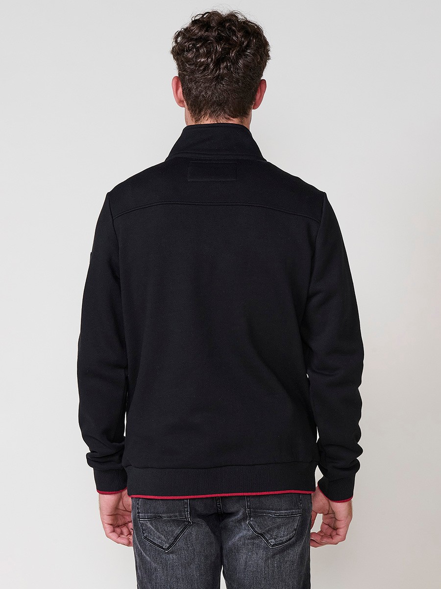 Sudadera de hombre en color negro con cuello alto y cierre de cremallera. Incluye estampado delantero, bolsillo con solapa abotonada y bolsillos laterales.