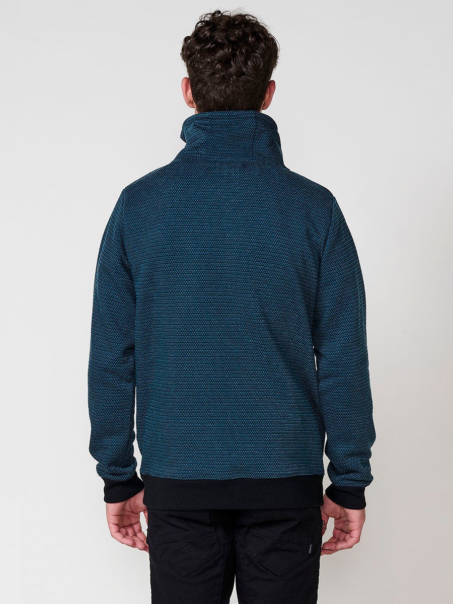 Sudadera de hombre en color petróleo con cuello alto y cremallera. Confeccionada en poliéster 100%, con estampado delantero para un estilo urbano y moderno.