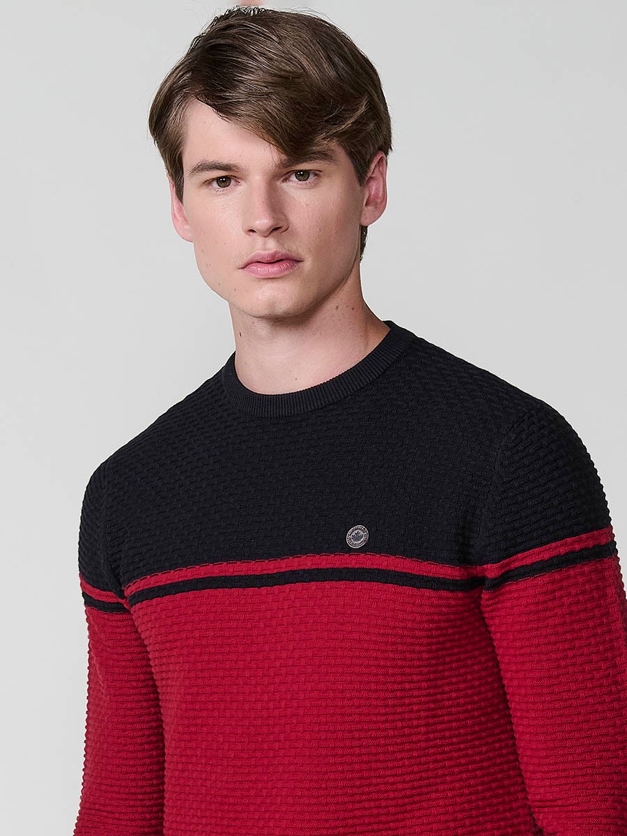 Jersey rojo de hombre en tricot con cuello redondo y manga larga. Confección 100% acrílico para un estilo moderno y atemporal.