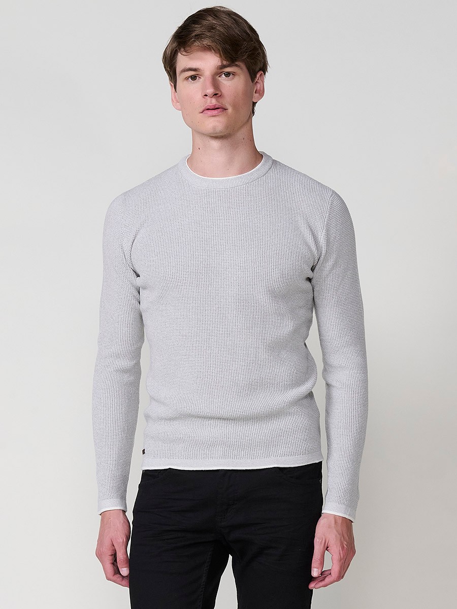 Jersey crudo de hombre en tricot con cuello redondo y manga larga. Tejido 100% acrílico, ligero, cómodo y atemporal.