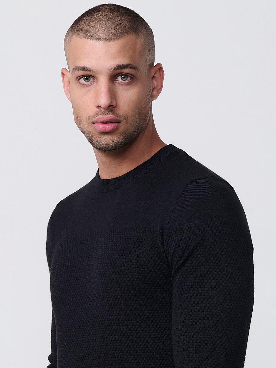 Jersey negro de hombre en tricot con cuello redondo y manga larga. Mezcla de viscosa, poliamida y poliéster, suave y versátil.