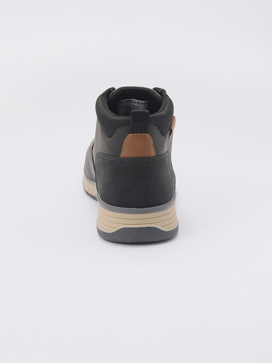 Botín de hombre en color negro con cordones, confeccionado en poliuretano y poliéster. Diseño moderno, resistente y versátil para el día a día.