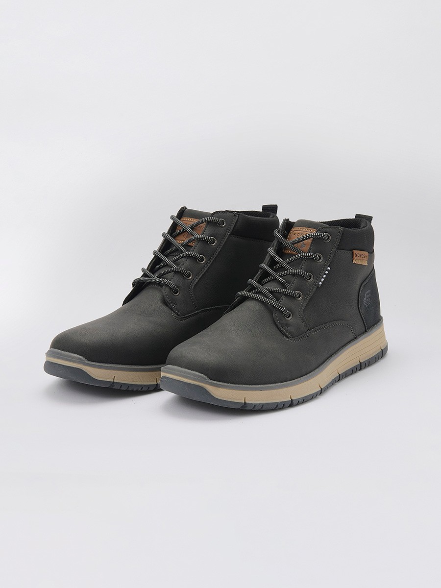 Botín de hombre en color negro con cordones, confeccionado en poliuretano y poliéster. Diseño moderno, resistente y versátil para el día a día.