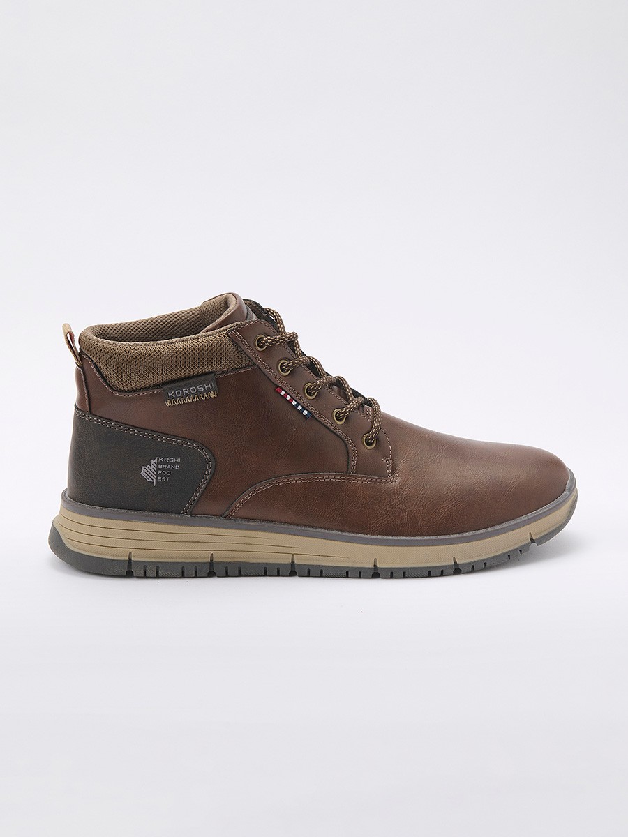 Botín de hombre en color marrón con cordones, confeccionado en poliuretano y poliéster. Diseño versátil, resistente y moderno para el día a día.
