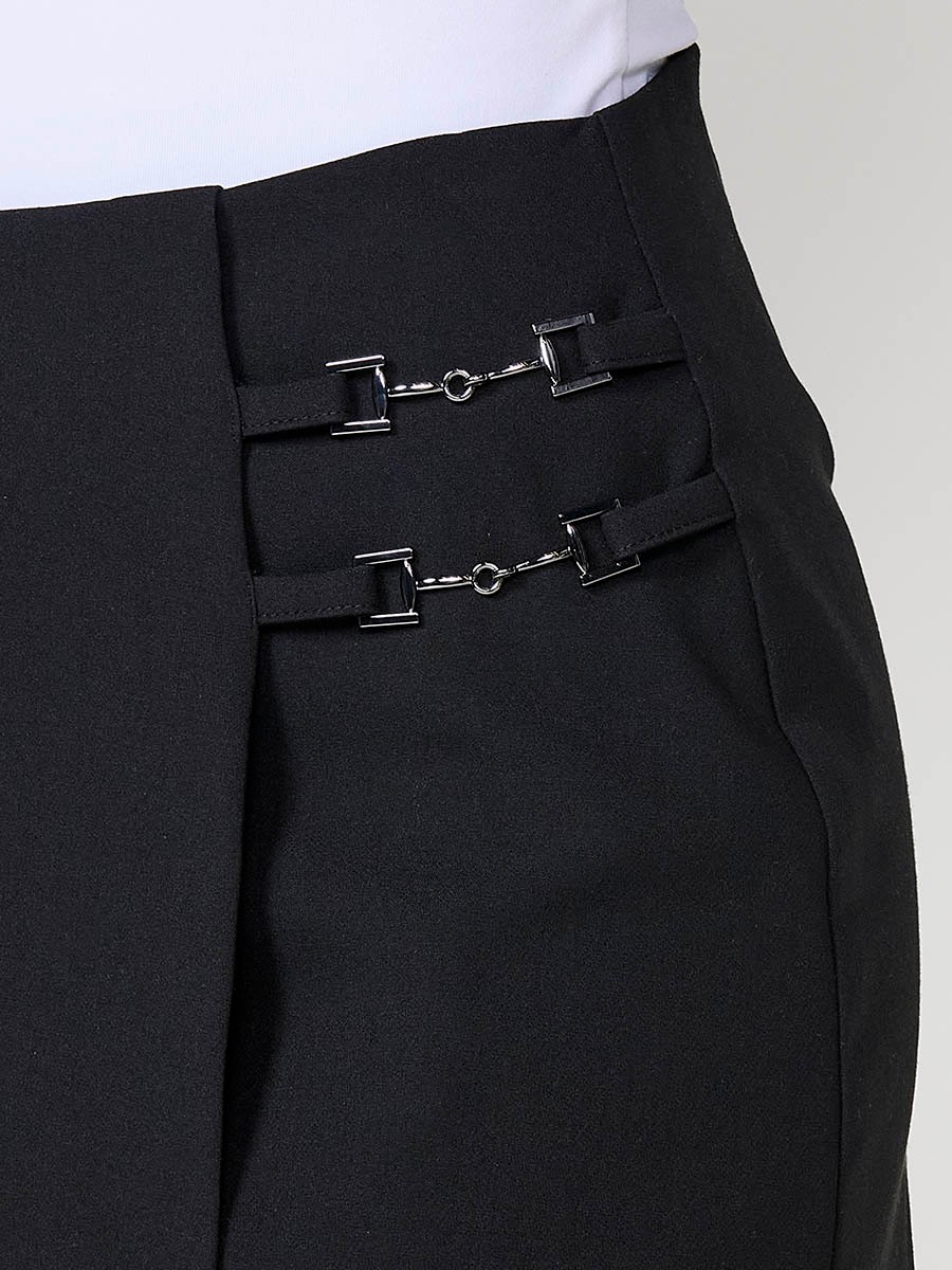 Falda elástica de mujer con diseño cruzado, hebillas metálicas y short interior. Cierre trasero con cremallera oculta.