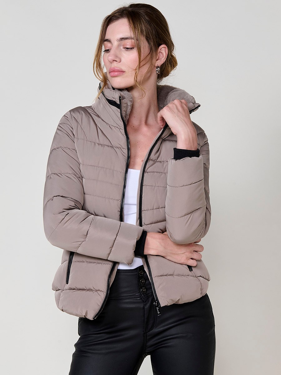 Chaqueta acolchada de mujer en color beige, cuello alto con forro efecto pelo, bolsillos laterales con cremallera y pespuntes canalé en los laterales.
