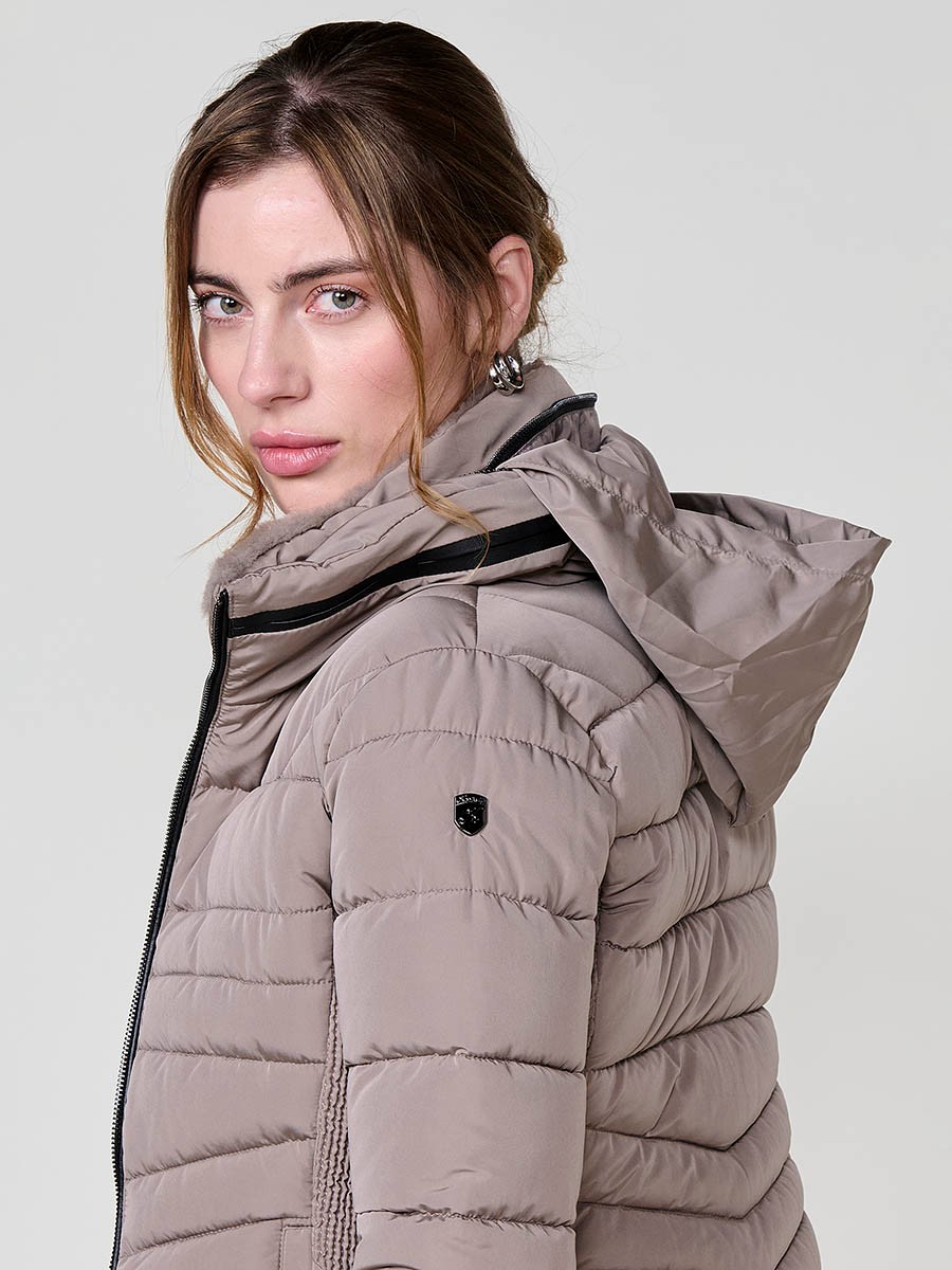 Chaqueta acolchada de mujer en color beige, cuello alto con forro efecto pelo, bolsillos laterales con cremallera y pespuntes canalé en los laterales.