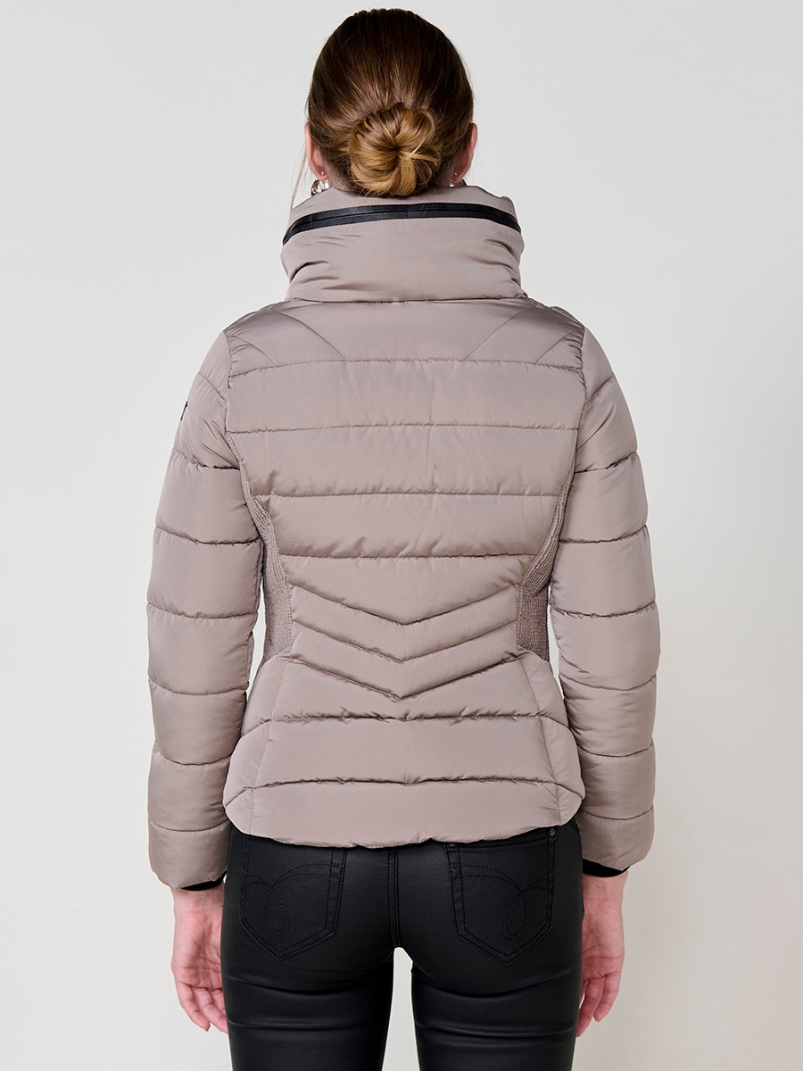Chaqueta acolchada de mujer en color beige, cuello alto con forro efecto pelo, bolsillos laterales con cremallera y pespuntes canalé en los laterales.