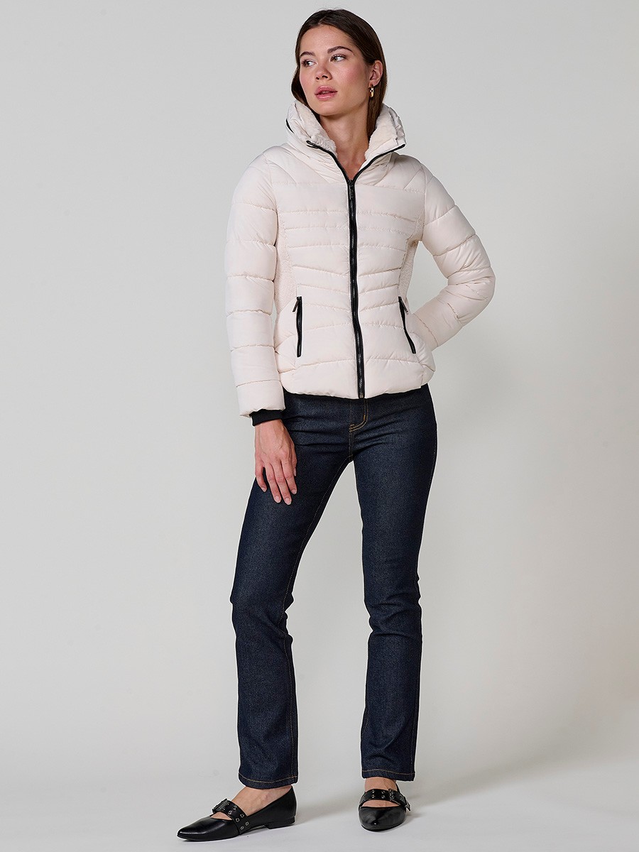Chaqueta acolchada de mujer en color crudo, cuello alto con forro efecto pelo, bolsillos laterales con cremallera y detalle de pespuntes canalé.