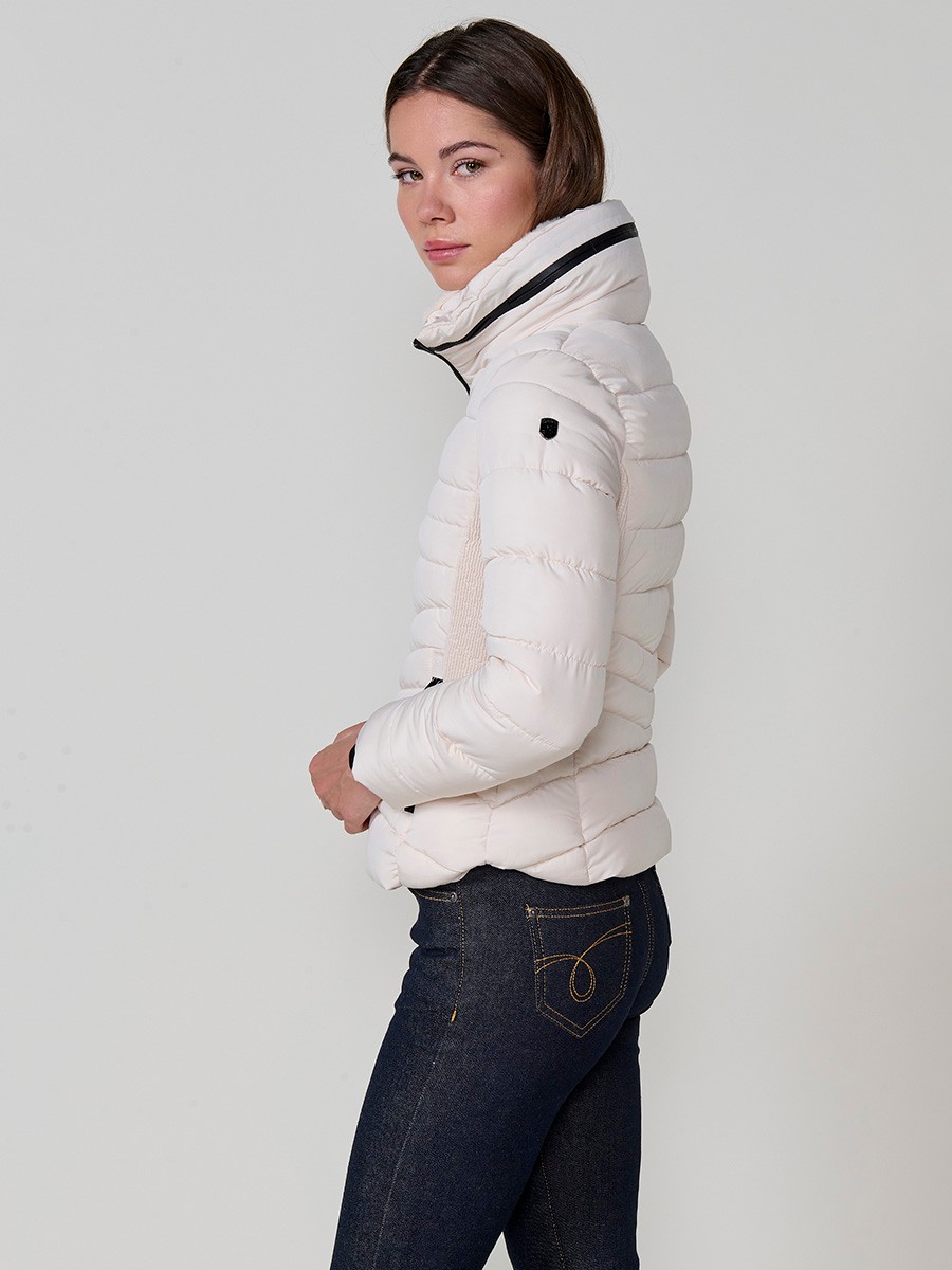 Chaqueta acolchada de mujer en color crudo, cuello alto con forro efecto pelo, bolsillos laterales con cremallera y detalle de pespuntes canalé.