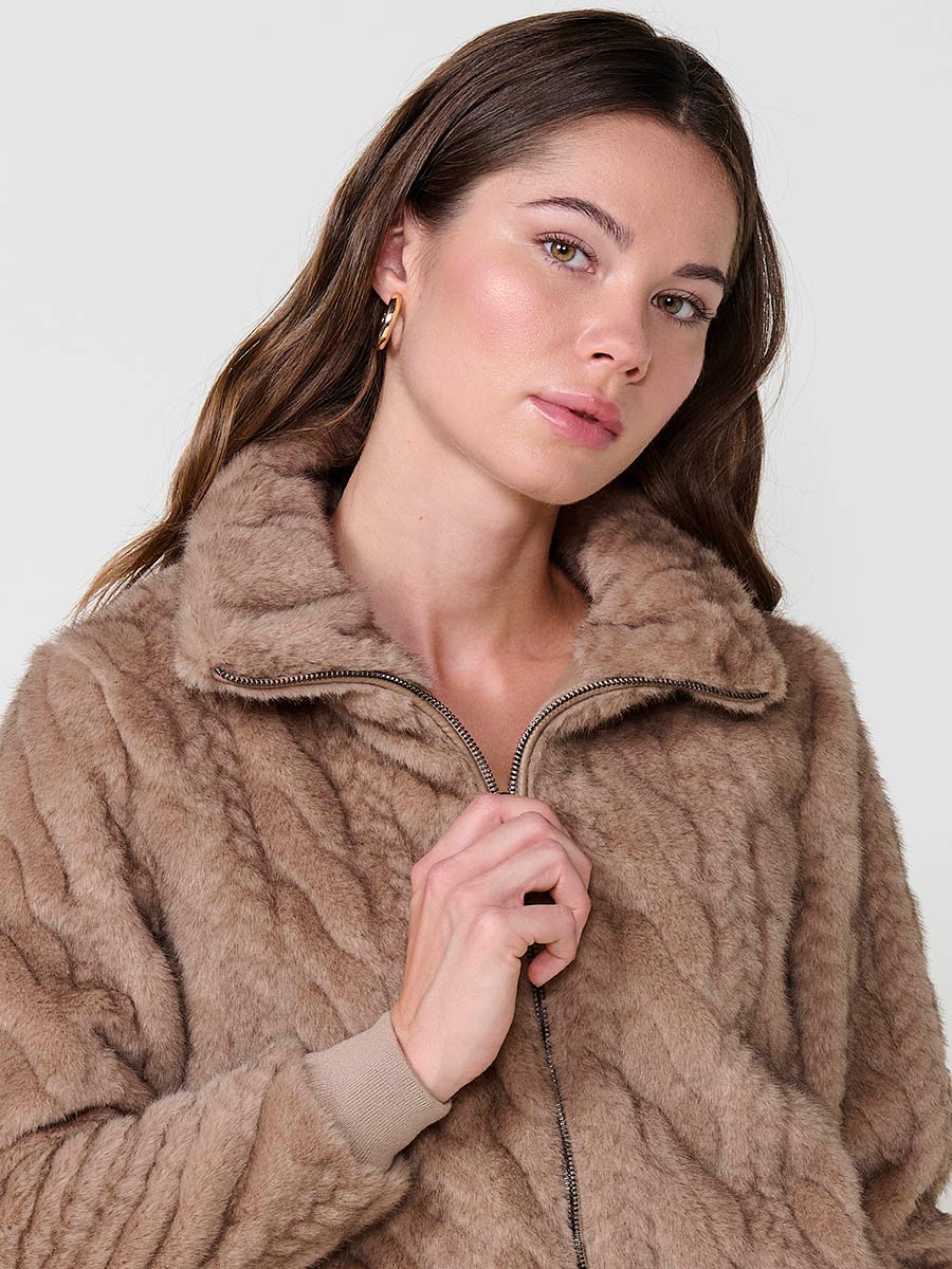 Chaqueta de mujer efecto pelo en color beige, cuello alto, cierre con cremallera metálica, bolsillos laterales y puños de canalé.