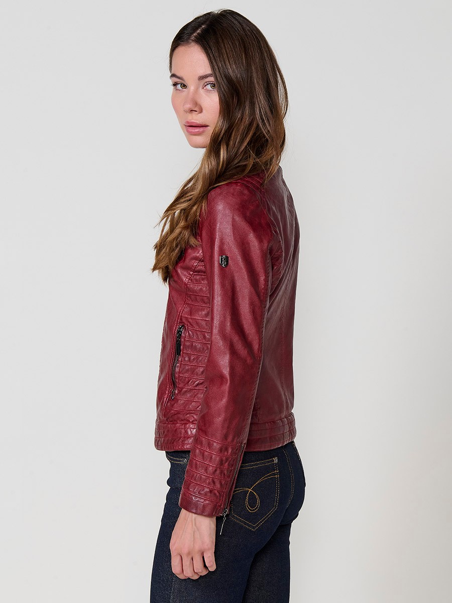 Women’s biker jacket in burgundy faux leather, mao collar, faux fur lining, quilted sleeves and metallic zippers.
