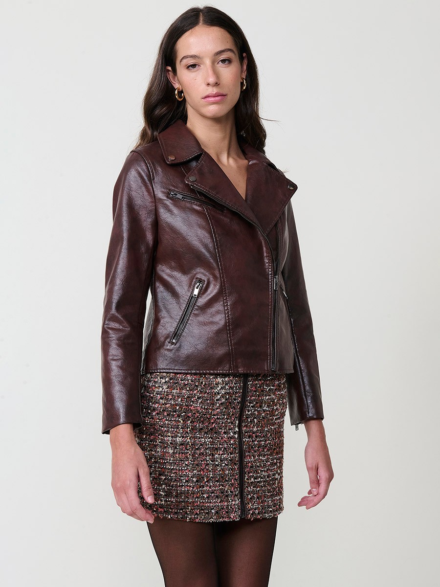 Women’s biker jacket in brown faux leather with quilted lining, metallic zipper pockets and stitched details.