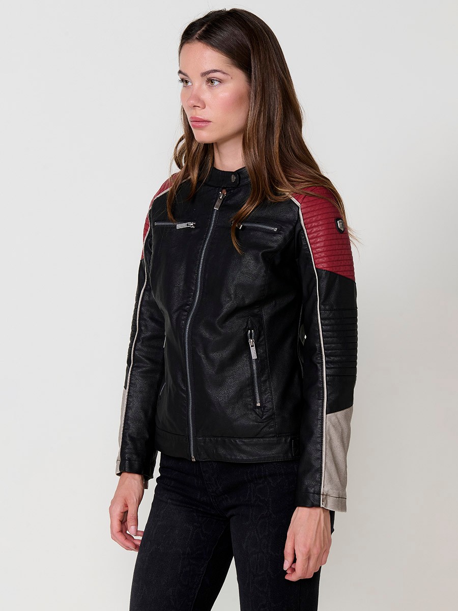 Women’s biker jacket in black faux leather with mao collar, contrast details, faux fur lining and metallic zippers.