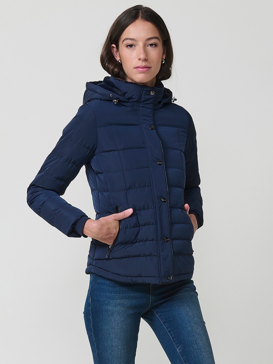 Chaqueta acolchada de mujer en color navy con cuello alto, capucha extraíble y forro efecto pelo. Prenda cálida y funcional con un estilo urbano y moderno.