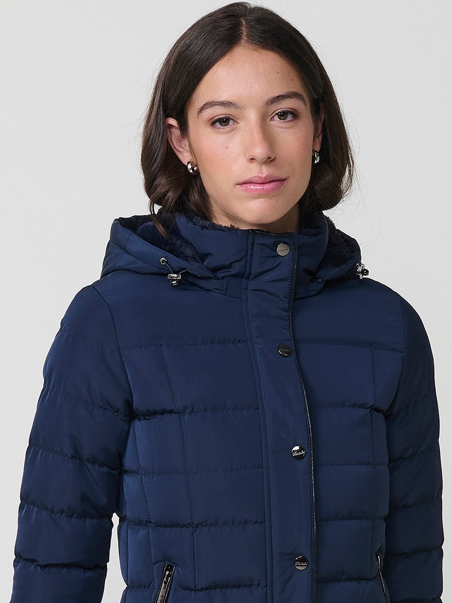Chaqueta acolchada de mujer en color navy con cuello alto, capucha extraíble y forro efecto pelo. Prenda cálida y funcional con un estilo urbano y moderno.