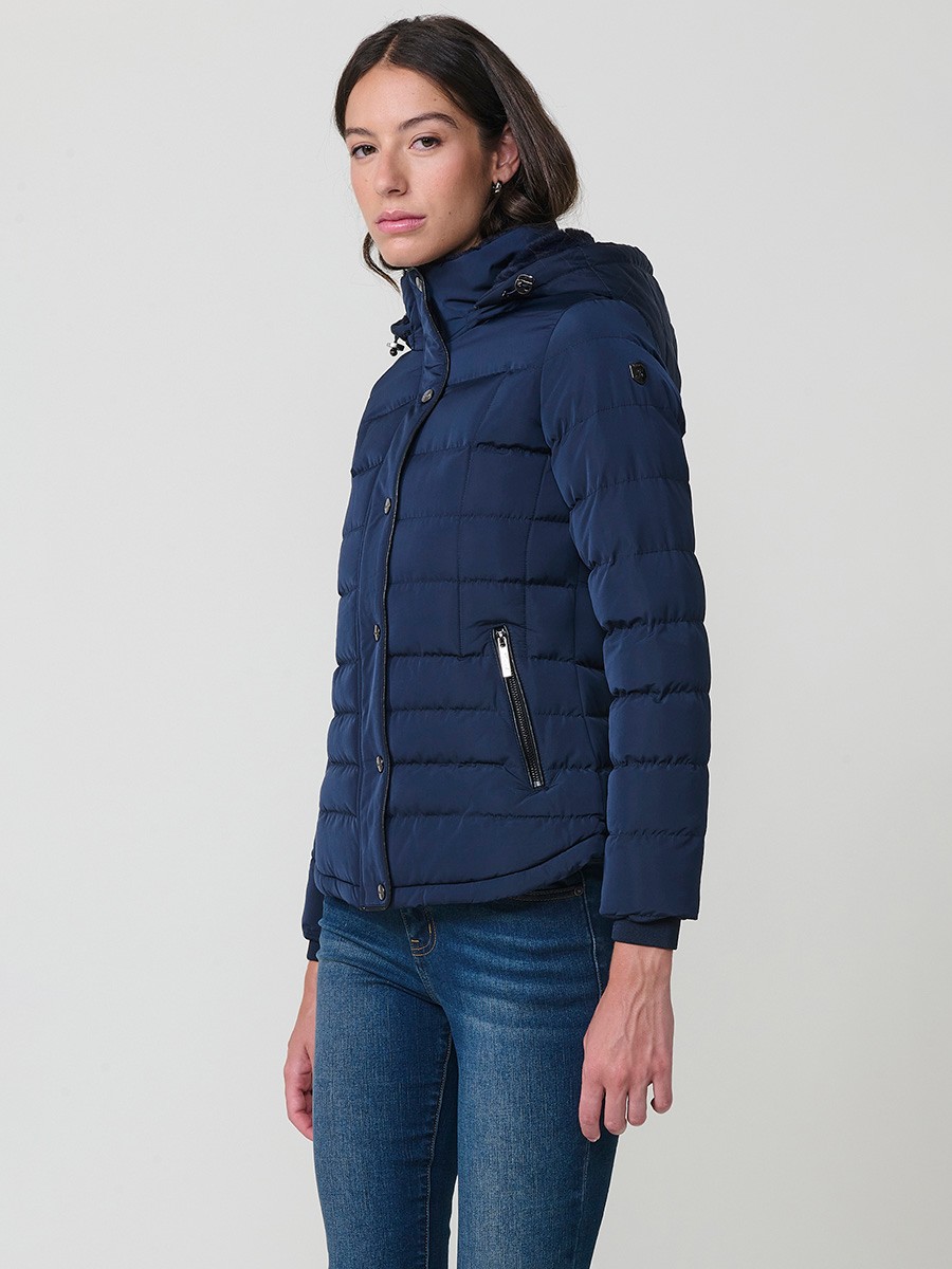 Chaqueta acolchada de mujer en color navy con cuello alto, capucha extraíble y forro efecto pelo. Prenda cálida y funcional con un estilo urbano y moderno.
