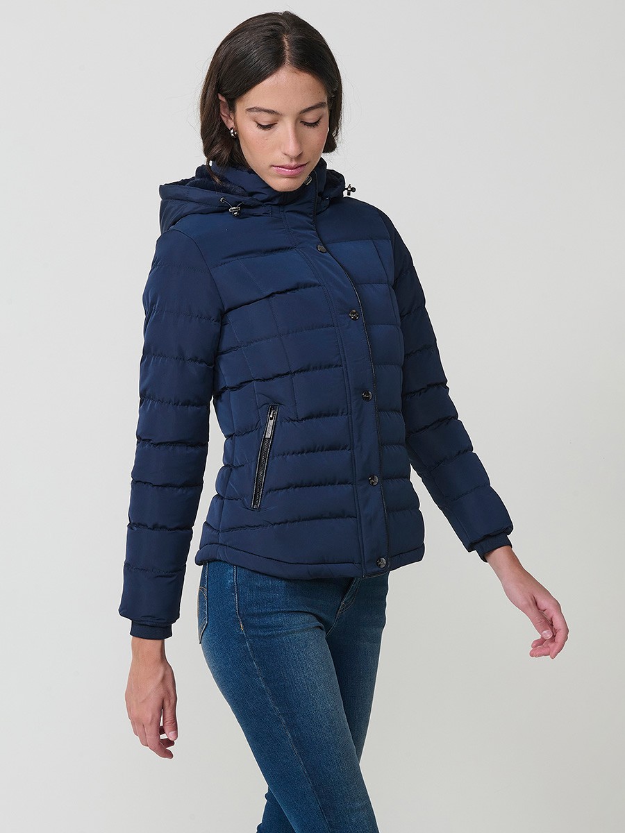 Chaqueta acolchada de mujer en color navy con cuello alto, capucha extraíble y forro efecto pelo. Prenda cálida y funcional con un estilo urbano y moderno.