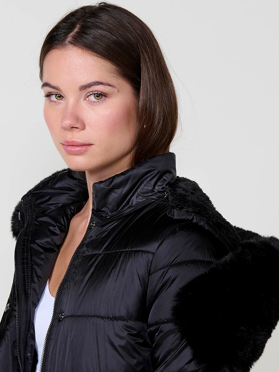 Chaqueta larga acolchada de mujer en color negro, cuello alto, capucha extraíble y forro en efecto pelo.