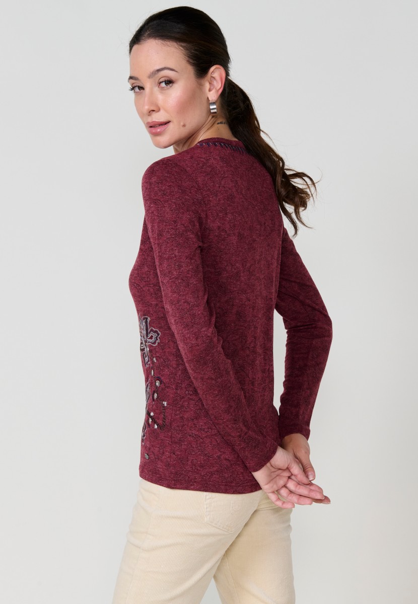 Camiseta de mujer roja de manga larga con cuello pico, tejido flamé melange, estampado floral y bordados. Detalle de tapeta con tres botones.