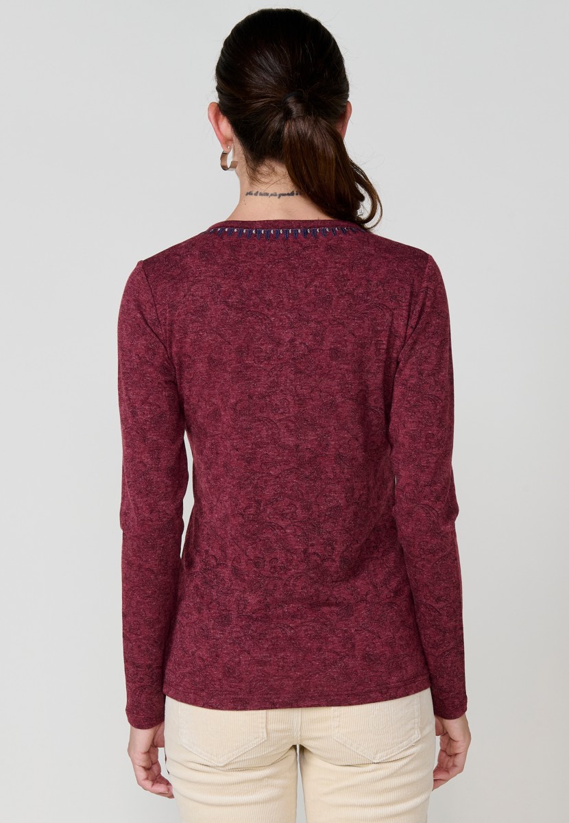 Camiseta de mujer roja de manga larga con cuello pico, tejido flamé melange, estampado floral y bordados. Detalle de tapeta con tres botones.