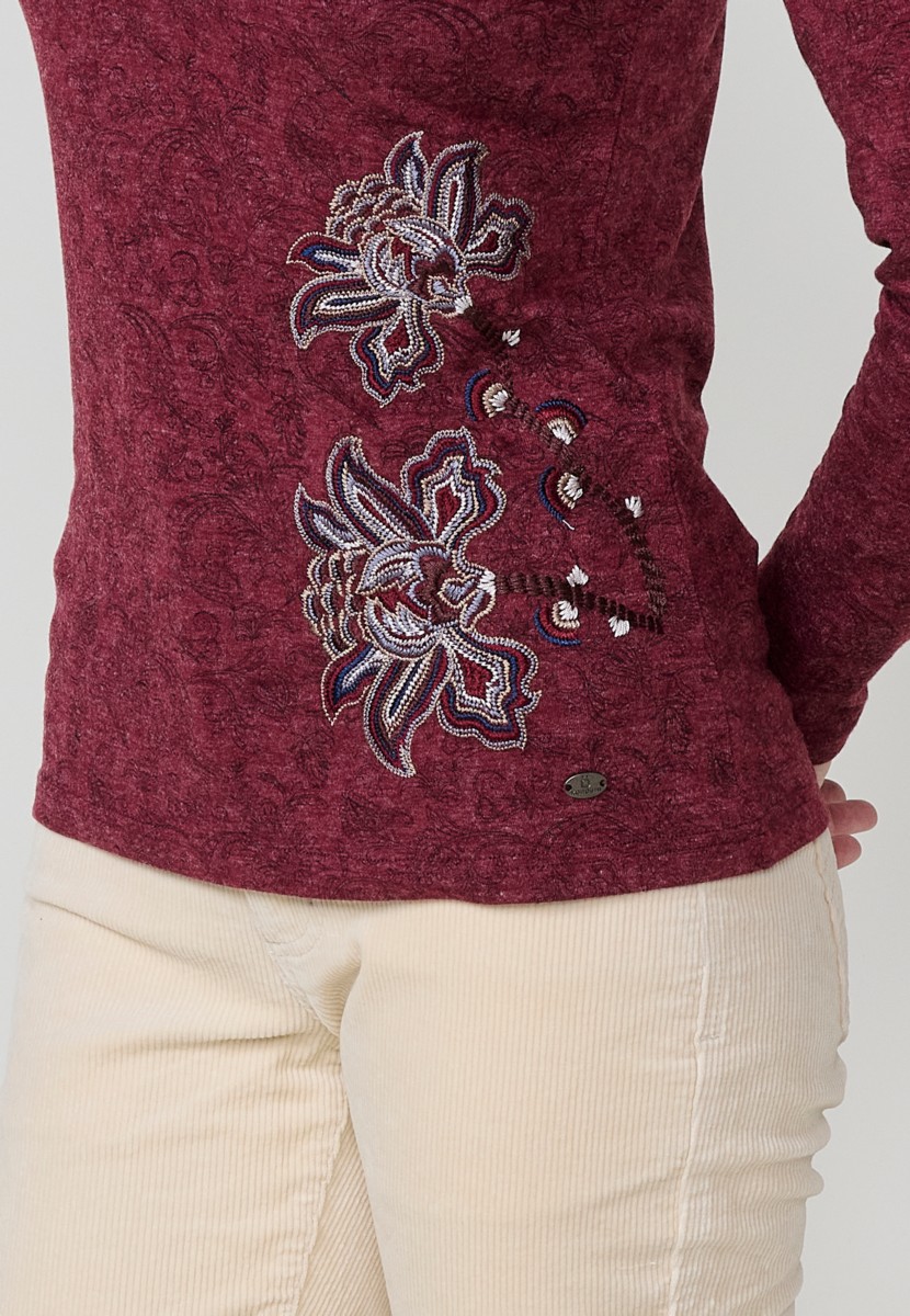 Camiseta de mujer roja de manga larga con cuello pico, tejido flamé melange, estampado floral y bordados. Detalle de tapeta con tres botones.