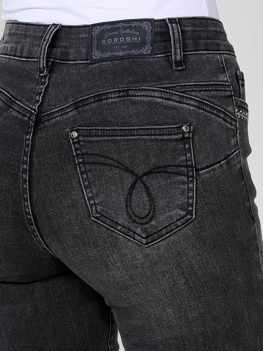 Jeans slim push up de mujer en denim negro elástico, con cinco bolsillos, cierre metálico y bordado frontal con brillos.