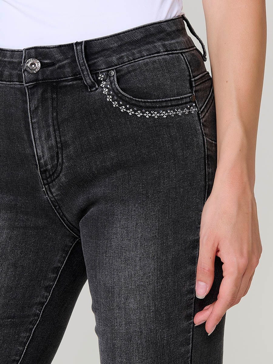 Jeans slim push up de mujer en denim negro elástico, con cinco bolsillos, cierre metálico y bordado frontal con brillos.