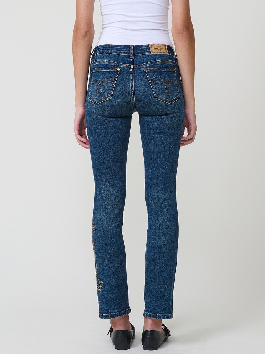 Jeans slim azul muy oscuro elásticos, tiro medio, cinco bolsillos, cierre metálico y bordado con brillos en bolsillo y bajo.