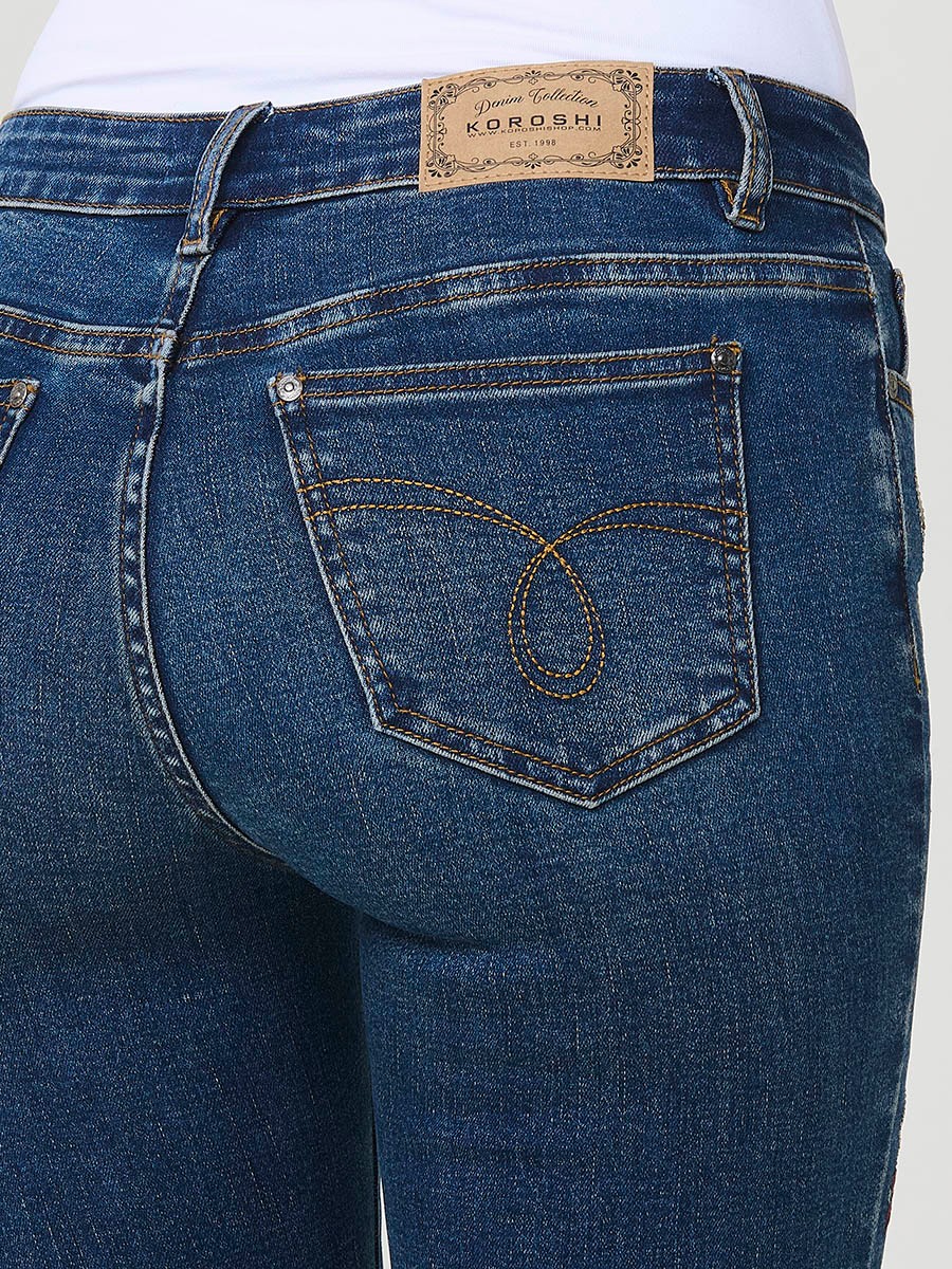 Jeans slim azul muy oscuro elásticos, tiro medio, cinco bolsillos, cierre metálico y bordado con brillos en bolsillo y bajo.
