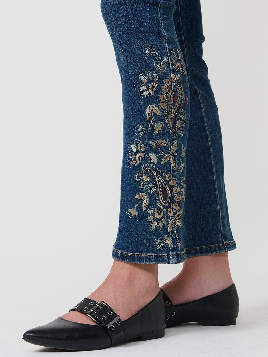 Jeans slim azul muy oscuro elásticos, tiro medio, cinco bolsillos, cierre metálico y bordado con brillos en bolsillo y bajo.