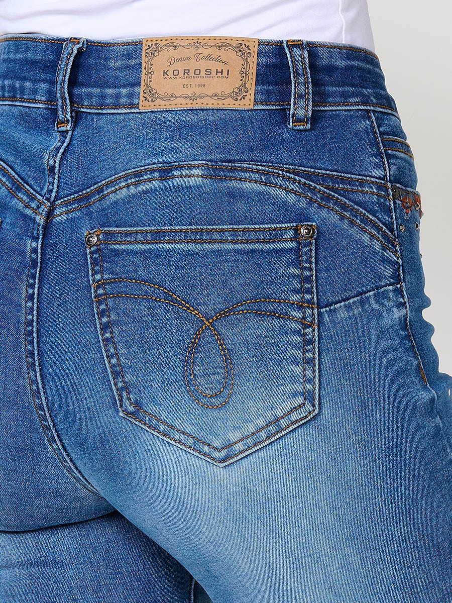 Jeans regular push up azul oscuro de mujer, tiro medio, cinco bolsillos, bordado con brillos y aberturas laterales en el bajo.