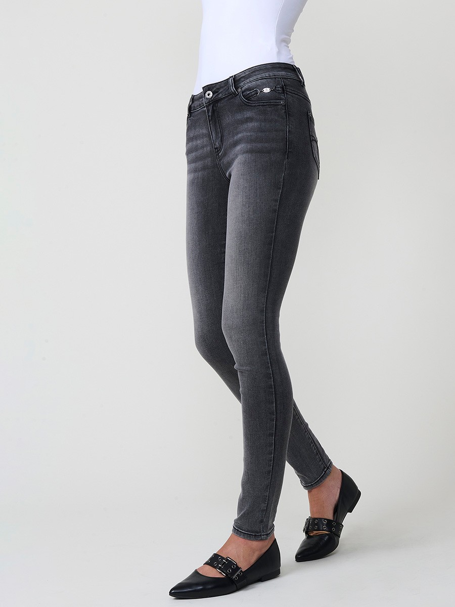 Jeans slim negro de mujer en denim elástico, tiro medio, cinco bolsillos, cierre metálico y placa Koröshi en el frontal.