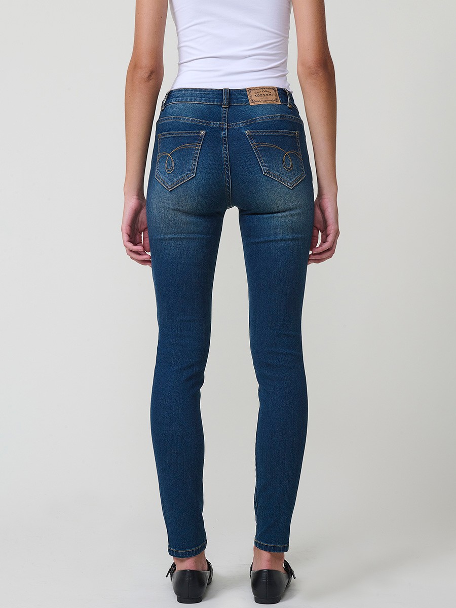 Pantalón slim de mujer en denim azul oscuro elástico, cinco bolsillos y placa metálica con logo Koröshi.