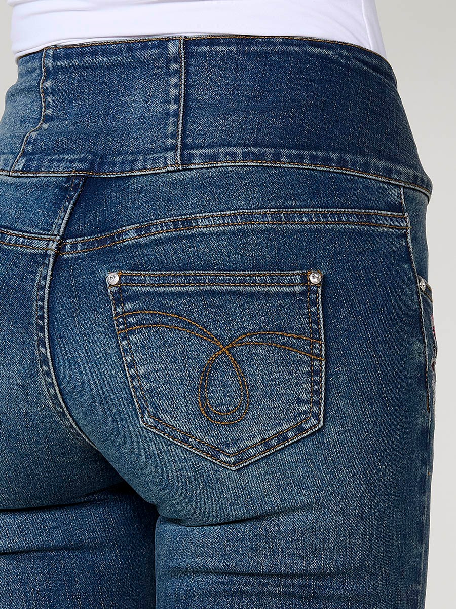 Jeans corset slim de mujer en denim azul oscuro elástico, tiro alto, cinco bolsillos y cierre con tres botones metálicos.