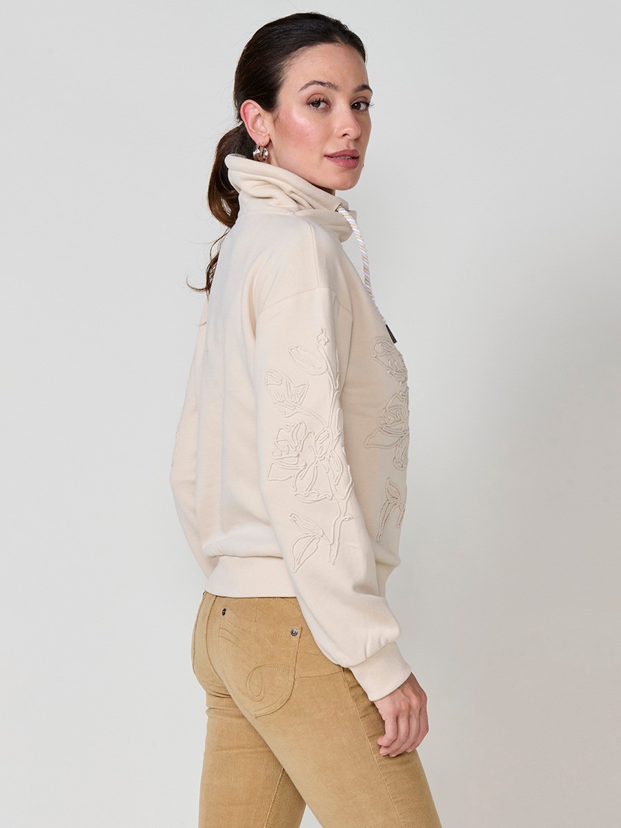 Sudadera de mujer con cuello alto ajustable, tejido doble cara, bordado floral en mini cordón y cordón tricolor con terminal metálico crudo.