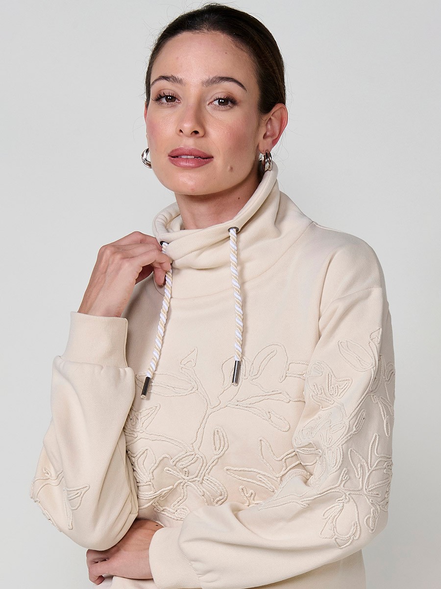 Sudadera de mujer con cuello alto ajustable, tejido doble cara, bordado floral en mini cordón y cordón tricolor con terminal metálico crudo.